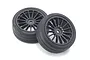 Two Kyosho black RC touring car wheels with grooved rubber tyres on a white background.
