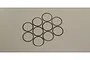Ten thin metal shims or washers arranged in a cluster on a plain light grey background.