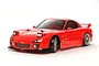 A studio shot of a red Tamiya Mazda RX-7 RC drift car model on a white background.