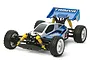 Tamiya Neo Scorcher 1/10 scale 4WD RC buggy kit, featuring a blue and white body, yellow coil-over shocks, and off-road spike tires on white wheels.