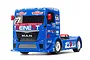 A Tamiya Team Reinert Racing MAN TGS RC racing truck in blue with white and red sponsor decals, viewed from a front three-quarter angle.