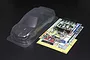An unpainted clear polycarbonate RC car body shell for a Subaru Impreza WRC, including decal sheets and plastic parts trees on a black background.