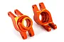 Two bright orange anodized aluminum rear stub axle carriers for a Traxxas 1/10 Maxx RC vehicle, shown from a side angle on a white background.