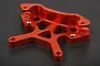 A bright orange anodized aluminium front shock tower for an RC car, featuring a complex CNC-machined design with multiple mounting holes.