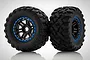 Two Traxxas Maxx 4S all-terrain RC tyres pre-glued to black 6-spoke wheels with blue beadlock-style rings, set against a white background.