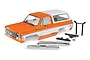 Traxxas TRX-4 1979 Chevrolet Blazer orange and white painted RC body shell with chrome bumpers and mounting hardware on a white background.