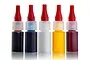 Five small plastic bottles of Scenic Colours dye from Deluxe Materials, featuring red applicator caps and various liquid colours, standing on a white surface.