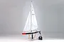 Kyosho Seawind RC racing yacht on a wooden display stand with a remote control transmitter on a plain grey background.