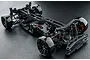 A high-angle studio shot of an assembled MST FXX 2.0 S RC drift car chassis on a dark textured surface.
