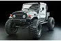 A grey MST CFX-W J45C RC rock crawler truck with large off-road tires, shown from a front three-quarter angle against a black background.