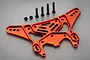 A red anodized aluminium rear shock tower for an RC car, accompanied by four black metal screws and two black nuts, set against a plain grey background.