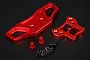 A Rovan red anodized aluminium front bumper kit including two machined metal bumper plates, two red spacers, and a set of black mounting screws.