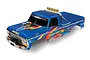 A blue Traxxas Bigfoot RC monster truck body shell with colorful decals, chrome roll bar, and KC light bar, isolated on a white background.