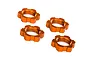 Four orange anodized aluminium splined wheel nuts for Traxxas RC vehicles arranged on a white background.