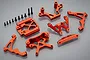 A set of orange anodized aluminium RC car front suspension parts including shock towers, suspension arms, and mounting hardware on a grey background.