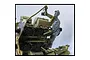 A 1/35 scale plastic model figure of a Flakvierling gunner seated at the controls of a military anti-aircraft gun.