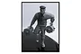 A 1/35 scale unpainted grey plastic model figure of a man wearing a cap and carrying two cylindrical canisters.