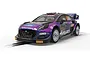 A 1/32 scale Scalextric Ford Puma WRC slot car in purple livery with sponsor decals, positioned on a slot car track section.