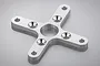 A silver-coloured, X-shaped aluminium motor mount for an RC plane, featuring a central hole and four mounting arms with countersunk screw holes.