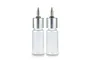 Two clear glass airbrush bottles with silver metal caps and pointed nozzles standing side by side.