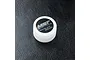 A small white plastic container of MST Black Grease, model 130008, sitting on a black textured surface.