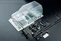 Unpainted clear polycarbonate RC car body shell for MST J3 with included plastic accessories, decals, and hardware on a dark background.