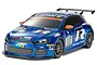 A studio shot of a Tamiya 1/10 scale Volkswagen Scirocco GT24 RC car in blue racing livery with sponsor decals on a white background.