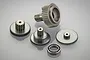 A set of four metal servo gears and one ball bearing arranged on a light grey background.