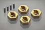 Four brass RC wheel hex adapters and four small metal drive pins arranged on a reflective grey surface.