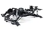 A studio shot of the Axial SCX10 III Base Camp RC rock crawler chassis kit, showing the black plastic frame, metal suspension links, and coil-over shocks.