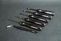 A set of five Koswork screwdrivers and one pair of tweezers arranged on a dark grey surface.