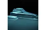 A clear, unpainted polycarbonate RC buggy body shell and a separate small wing piece on a dark background.