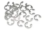 A collection of small silver-coloured metal E-clips scattered on a white background.