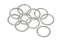A collection of ten thin, silver-coloured metal shim washers scattered on a white background.