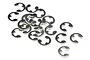 A collection of small silver-coloured metal E-clips scattered on a white background.