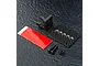 MST black aluminium rear ESC mount kit including a metal bracket, carbon fiber plate, double-sided tape, and various screws on a textured black surface.