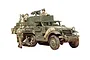 A 1/35 scale Tamiya plastic model of a U.S. M3A2 half-track vehicle, painted in olive drab with several soldier figures and a mounted machine gun.