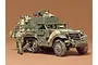 A 1/35 scale Tamiya model of a U.S. M16 half-track vehicle with painted crew figures, displayed against a plain brown background.