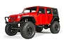 A red Axial SCX10 Jeep Wrangler Unlimited Rubicon RC rock crawler, featuring large off-road tires, a black front bumper, and a detailed scale body.