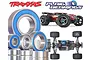 A collection of metal ball bearings with blue rubber seals displayed alongside a Traxxas E-Revo RC car and the Plaig Bearings logo.