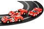 Three red Scalextric 1/32 scale slot cars numbered 23, 24, and 26 racing on a curved black slot car track.