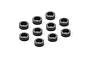 Ten small black cylindrical aluminium shims arranged on a white background.