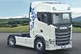 A white Scania S770 V8 truck model with a blue griffin logo on the side, parked on an asphalt road against a landscape background.