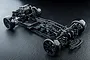 A high-angle studio shot of an assembled MST RMX EX GT 1/10 scale RWD RC drift car chassis on a dark textured surface.