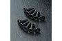 A set of ten black metal countersunk hex head screws arranged in two rows on a textured black surface.