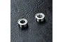 Two small metal shielded ball bearings placed on a textured black surface.