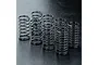 A set of eight black metal RC shock absorber coil springs arranged on a dark textured surface.
