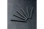 Six long, threaded metal grub screws arranged in a fan shape on a black textured surface.