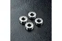 Four metal shielded ball bearings arranged on a textured black surface.