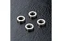 Four small silver-coloured metal bushings arranged on a textured black surface.